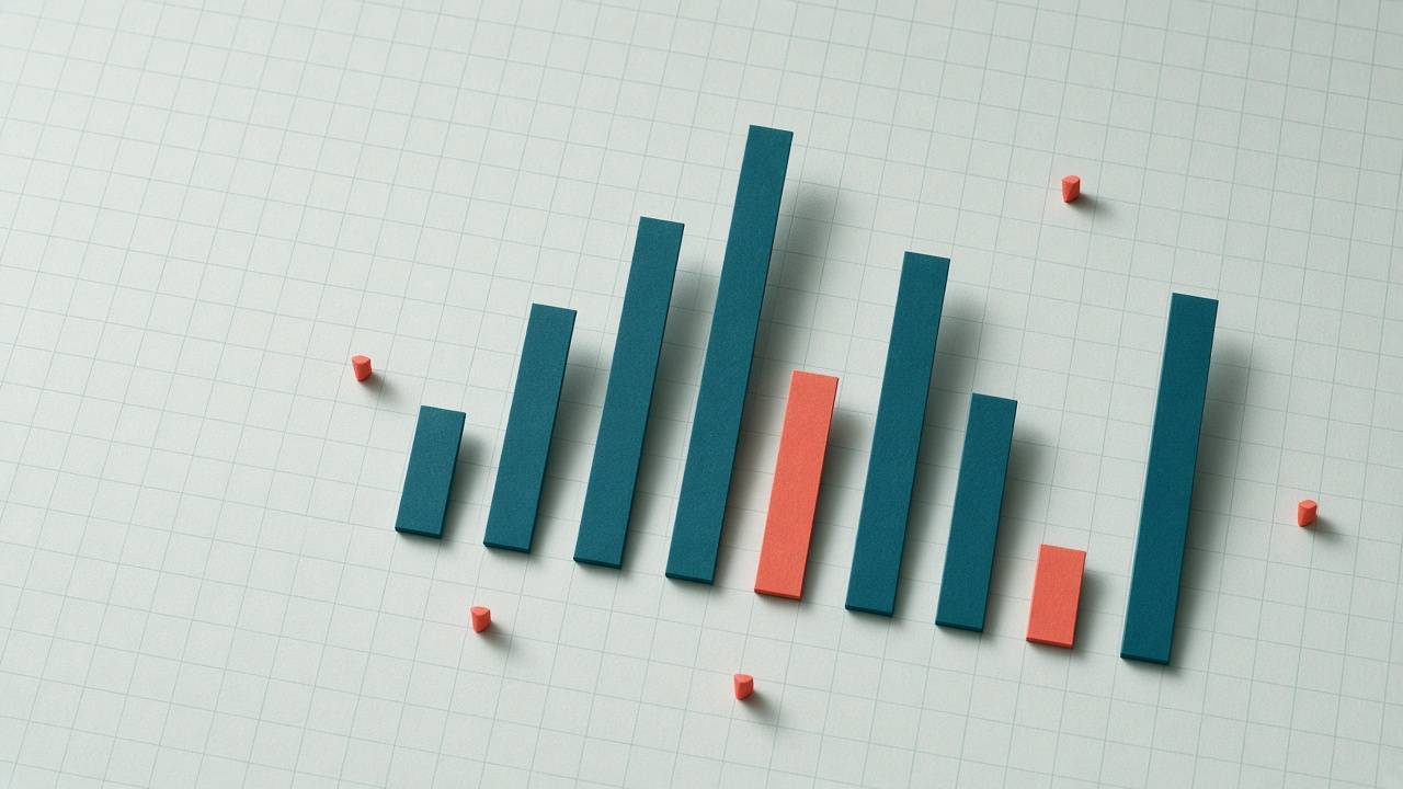 A bar chart built from teal and coral paper strips standing on graph paper, with small coral pins around it